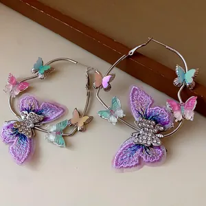 Detail showing embroidered butterfly and rhinestone accents on silver hoop earrings.