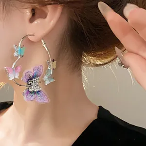 Detail of silver hoop earring featuring embroidered butterflies and crystal accents.