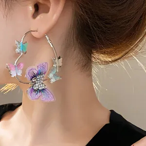 Close-up of heart-shaped hoop earring featuring embroidered butterflies and rhinestones