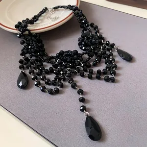 Détail d'un collier de perles en cristal noir multicouche avec d'élégants pendentifs gouttes.