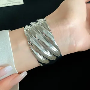 Close-up view of a wide silver cuff bracelet featuring a unique wavy metal texture