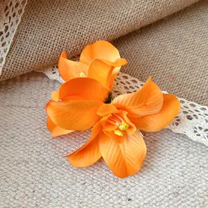 Gros plan d'une pince à cheveux fleur en tissu orange vif avec des étamines jaunes réalistes