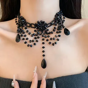 Gros plan d'un collier ras-du-cou multicouche en cristal noir avec pendentifs goutte.