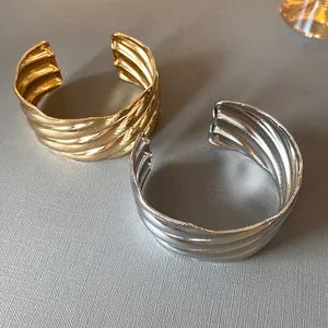 Detailed view of fashionable gold and silver metal cuff bracelets with wave textures