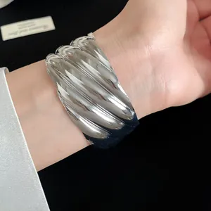 Close-up detail of silver wave texture metal open cuff bracelet on a model wrist