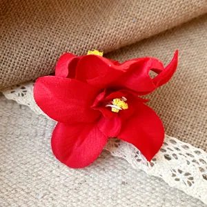 Close-up of vibrant red fabric flower hair clip with realistic yellow stamens.