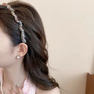 Detail view of a vintage style irregular acrylic stone headband worn by a model.