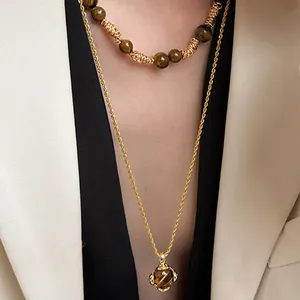 Detail einer mehrlagigen Tigerauge-Halskette mit goldener Kordelkette an einem Model