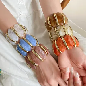 Detail von farbenfrohen, unregelmäßigen Acryl-Diamant-Armbändern mit Goldakzenten.