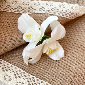 Detailed macro shot of a white fabric flower hair clip on rustic burlap background.