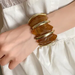 Detailansicht eines bernsteinfarbenen elastischen Acryl-Armbands mit Rauten am Handgelenk.