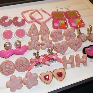 Detailed view of a variety of sweet pink heart and bear themed stud earrings.