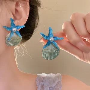 Detailed view of ocean-themed blue starfish and seashell earrings with white pearl center