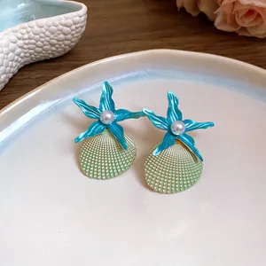 Detailed view of ocean-themed blue starfish and seashell stud earrings with central pearls