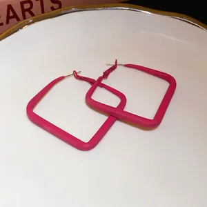 Detail view showing the elegant pink square hoop earrings with matte spray finish