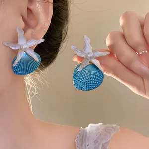 Detailed close-up of pearl starfish and blue shell earrings for seaside vacation
