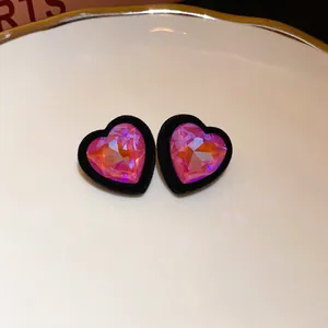 Detailed macro view of pink crystal heart earrings with a soft black velvet border