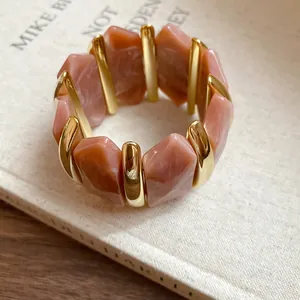 Nahaufnahme von unregelmäßigen Acryl-Rhombus-Perlen und goldenen Trennern am Armband