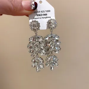 Detailed macro view of silver needle earrings featuring sparkling crystal wheat leaf design