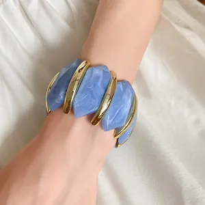 Nahaufnahme eines blauen Acryl-Armbands mit Marmormuster und goldenen Metallelementen