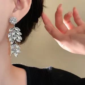 Macro detail of sparkling rhinestone flower and wheat spike drop earrings on model