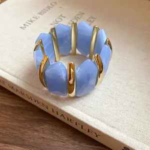 Makroansicht von blauem Acryl-Armband mit unregelmäßigen Rauten und goldfarbenen Metallelementen