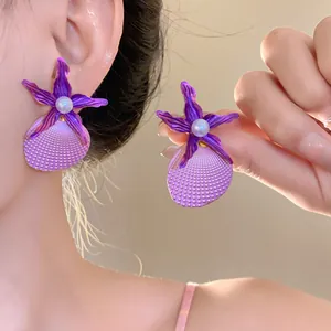 Detailed view of purple starfish shell earrings with central pearl for beach style