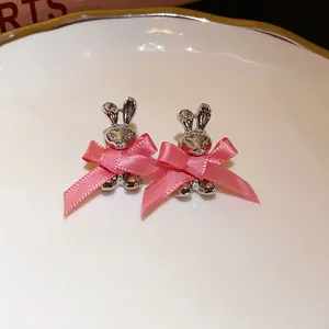 Detailed view of silver bunny stud earrings decorated with charming pink ribbon bows