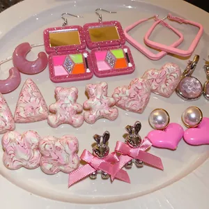 Collection of pink aesthetic earrings including heart, bear, and bunny shapes on a white plate