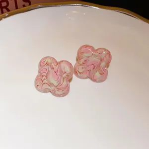 Detailed macro view of pink and white marbled clover stud earrings on a white plate