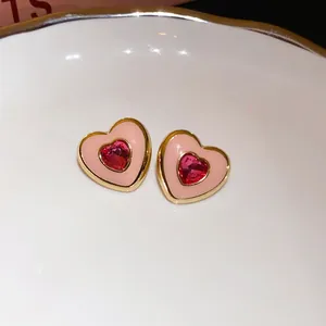 Detailed view of sweet pink heart-shaped stud earrings featuring a red crystal center stone