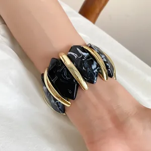 Detailansicht eines elastischen Acryl-Armbands mit unregelmäßigem schwarzem Marmormuster.
