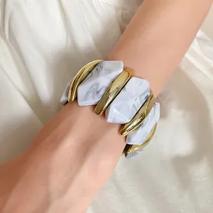 Detaillierte Makroansicht von grauem Marmormuster und poliertem Goldfinish am elastischen Armband