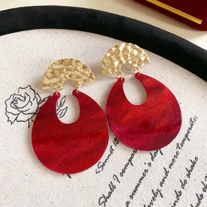 Close-up detail of vintage red marbled resin earrings with hammered gold metal top.