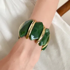 Nahaufnahme eines grünen Acryl- und Gold-Stretch-Armbands am Handgelenk einer Frau