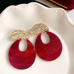 Detailed view of vintage red marbled U-shaped earrings with hammered gold metal accents