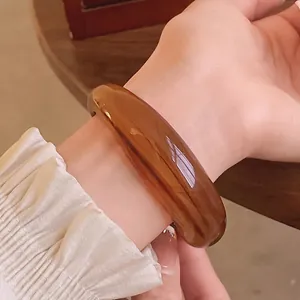 Elegant amber acrylic open bangle bracelet featuring a unique marbled texture on wrist