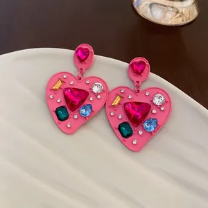 Detailed macro view of pink heart-shaped earrings featuring vibrant multi-colored gemstones.