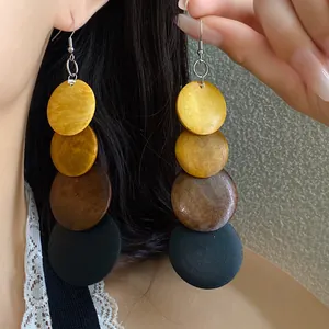 Close-up showing retro ethnic wooden drop earrings with gradient circles on model