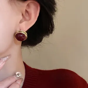Elegantes pendientes retro redondos retorcidos con perla roja oscura en la oreja de mujer