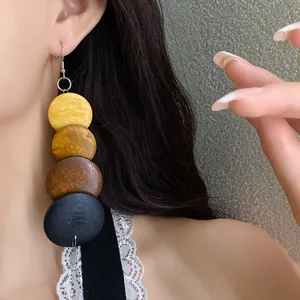 Close-up detail of retro ethnic style wooden drop earrings worn by an Asian model