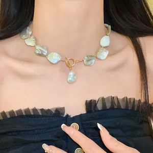 Modell trägt eine unregelmäßige ovale Muschelkette mit einem goldenen Knebelverschluss