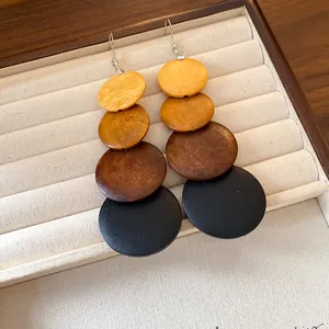 Close-up of ethnic style wooden dangling earrings with four-color gradient discs.