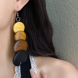 Macro detail of ethnic style multi-color wooden disc drop earrings on female model