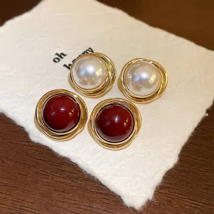 Primer plano de pendientes retro con perla sintética y piedra roja en tono dorado