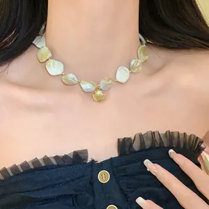 Nahaufnahme einer Muschelkette mit goldenem Anhänger an einem Model