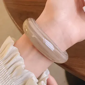 Close-up of a glossy acrylic bangle with elegant marble texture shown on the wrist