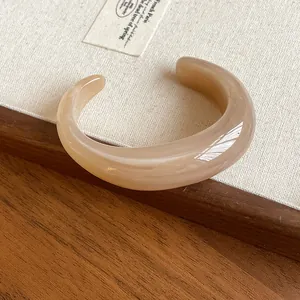Close-up of a glossy acrylic marbled cuff bracelet on a natural linen background
