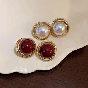 Primer plano del diseño trenzado de los pendientes de perla blanca y color burdeos