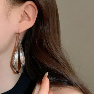Silver irregular twisted metal long earrings shown on a model for a stylish look